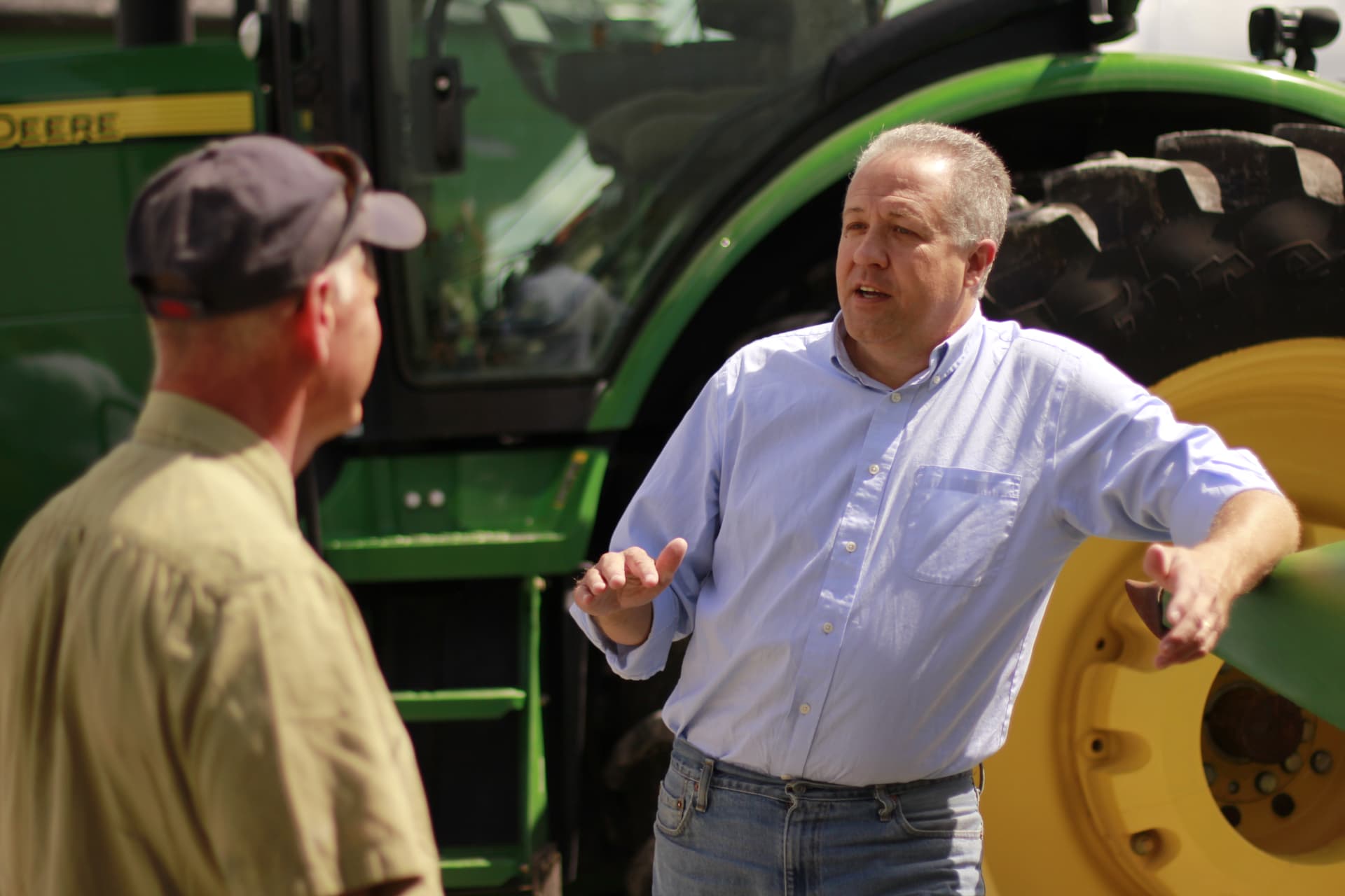 Mike Gaskill talking with a farmer in front of farm equipment